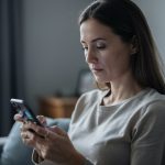 Comment retrouver le propriétaire d’un numéro commençant par 06 sans rappeler ce numéro ? Une femme consulte son smartphone après avoir remarqué un appel manqué, dans une ambiance sobre et réaliste.